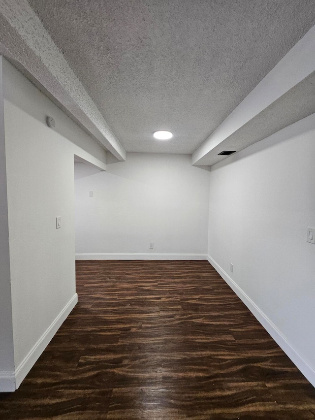 basement with a textured ceiling and dark wood-type flooring