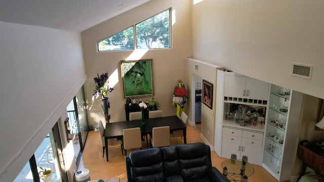 living room featuring a towering ceiling and light wood-type flooring