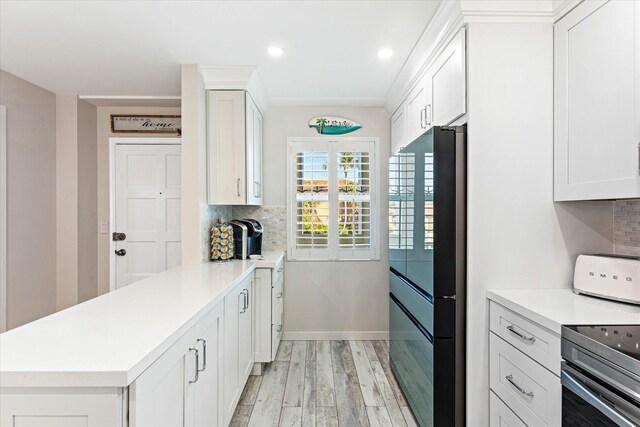 kitchen with black fridge, kitchen peninsula, tasteful backsplash, light hardwood / wood-style floors, and white cabinetry