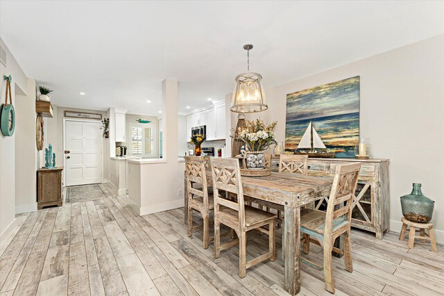 dining area with light hardwood / wood-style flooring and a notable chandelier