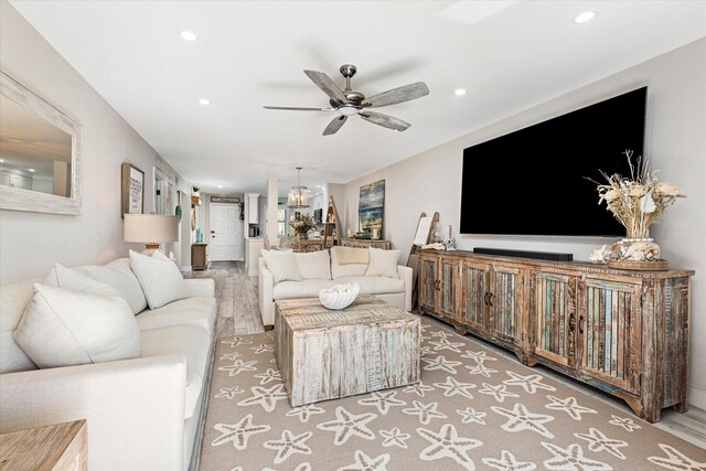 living room featuring ceiling fan with notable chandelier and hardwood / wood-style flooring