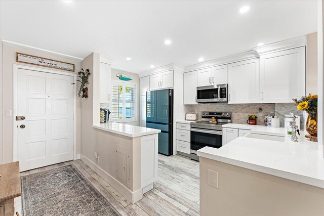 kitchen with stainless steel appliances, backsplash, kitchen peninsula, white cabinets, and light wood-type flooring