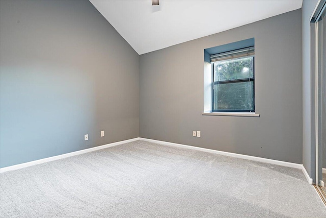 carpeted empty room featuring lofted ceiling