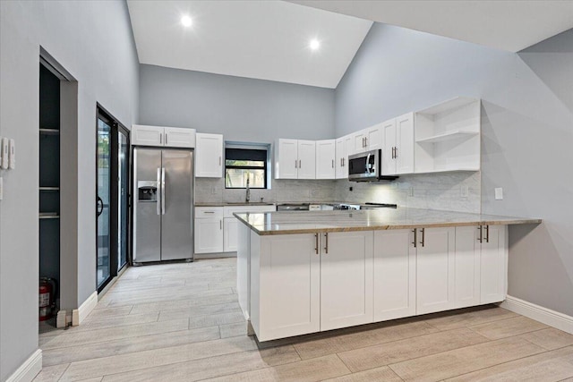 kitchen with white cabinetry, kitchen peninsula, appliances with stainless steel finishes, and light hardwood / wood-style flooring