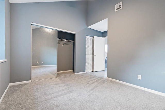 unfurnished bedroom with light colored carpet and a high ceiling