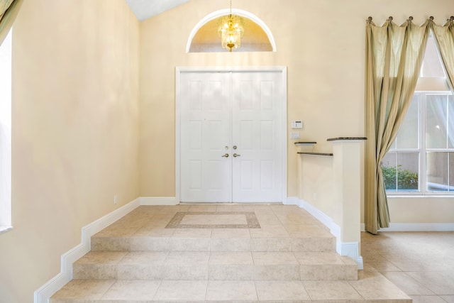 foyer entrance featuring baseboards, vaulted ceiling, light tile patterned flooring, and an inviting chandelier