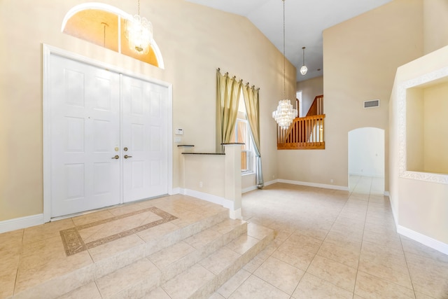 entryway with arched walkways, light tile patterned floors, visible vents, baseboards, and vaulted ceiling