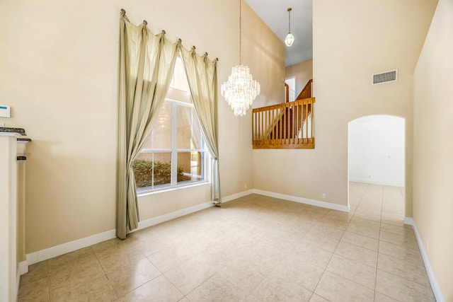 unfurnished room with an inviting chandelier, baseboards, visible vents, and arched walkways