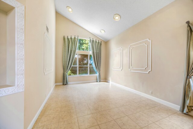 unfurnished room featuring lofted ceiling, light tile patterned floors, visible vents, and baseboards