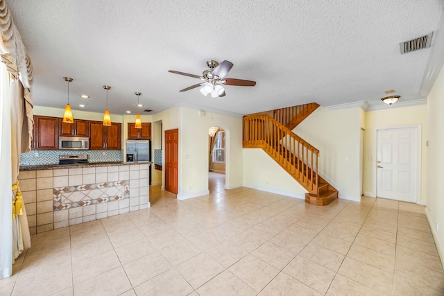 kitchen featuring visible vents, decorative backsplash, appliances with stainless steel finishes, brown cabinetry, and a ceiling fan