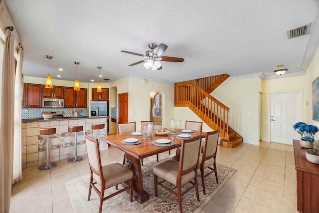 dining space with stairs, a ceiling fan, visible vents, and light tile patterned flooring