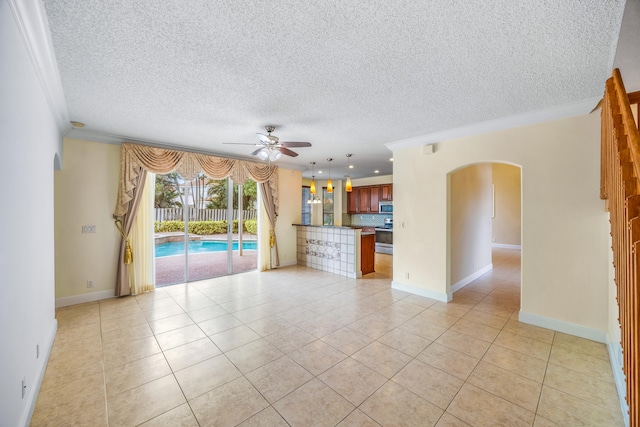 unfurnished living room with arched walkways, light tile patterned floors, ceiling fan, a textured ceiling, and baseboards