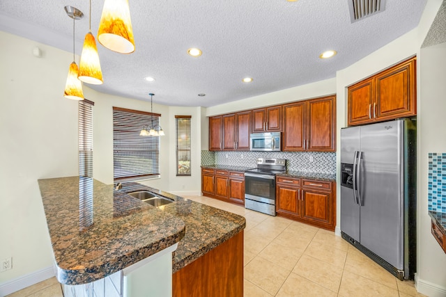 kitchen with stainless steel appliances, a sink, visible vents, hanging light fixtures, and backsplash