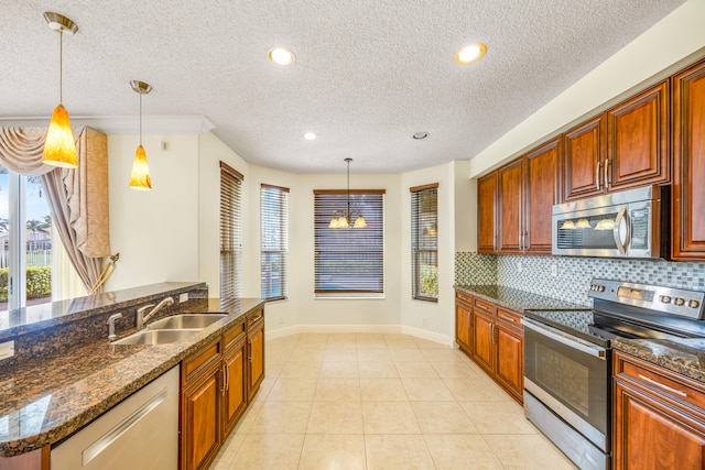 kitchen with light tile patterned floors, hanging light fixtures, decorative backsplash, appliances with stainless steel finishes, and a sink