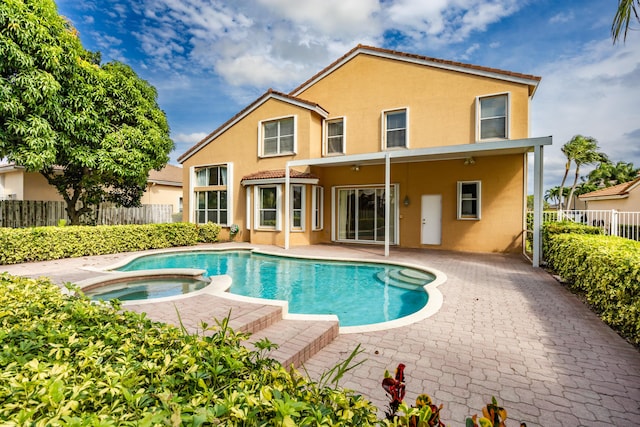 back of property with a patio area, a pool with connected hot tub, fence, and stucco siding