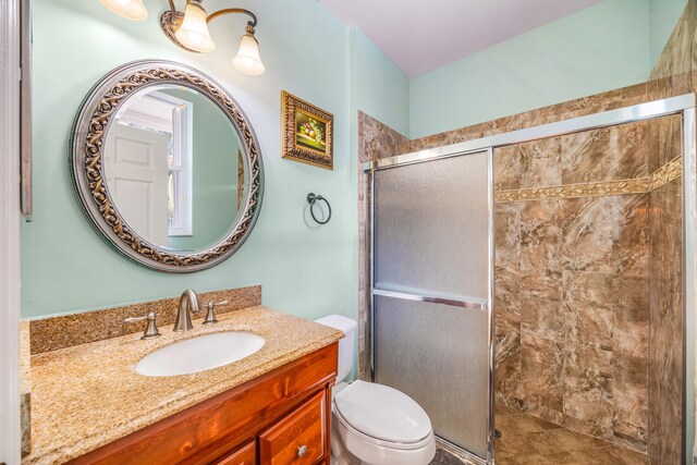 full bath featuring a stall shower, vanity, and toilet