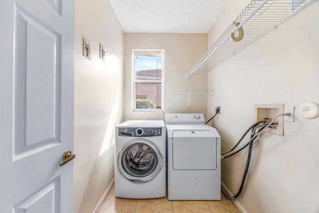 laundry room with light tile patterned floors, a textured ceiling, separate washer and dryer, laundry area, and baseboards