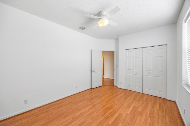 unfurnished bedroom with a textured ceiling, visible vents, baseboards, a ceiling fan, and light wood finished floors