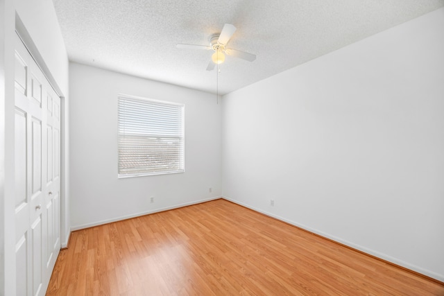 unfurnished bedroom with a textured ceiling, ceiling fan, baseboards, a closet, and light wood finished floors