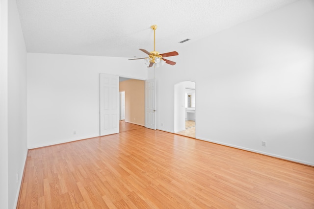 spare room with visible vents, arched walkways, a ceiling fan, a textured ceiling, and light wood-style floors