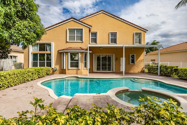 back of property featuring a patio area, fence, a pool with connected hot tub, and stucco siding