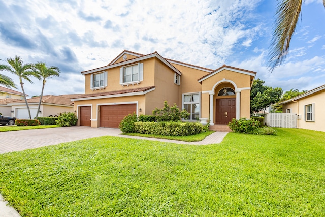 mediterranean / spanish-style home featuring a garage, stucco siding, a tile roof, decorative driveway, and a front yard