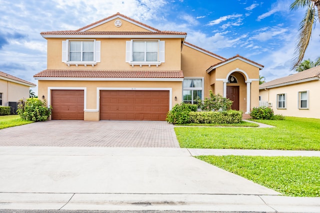 mediterranean / spanish home featuring a tiled roof, a front lawn, decorative driveway, and stucco siding