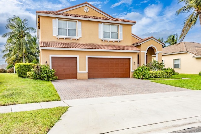 mediterranean / spanish house with decorative driveway, a tiled roof, an attached garage, and stucco siding