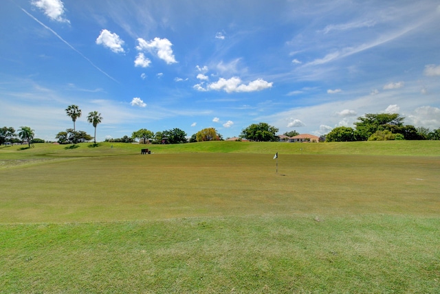 view of property's community with view of golf course and a lawn