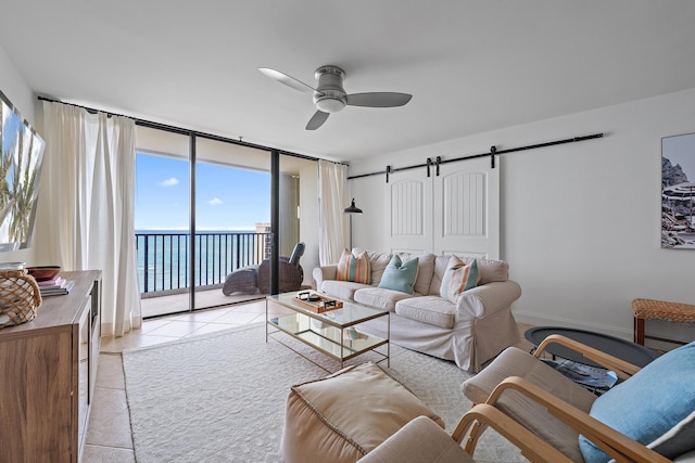 living room featuring ceiling fan, a barn door, a water view, and expansive windows