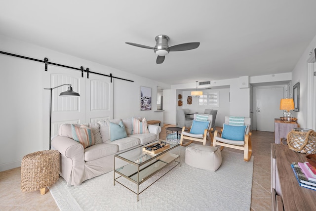 tiled living room featuring a barn door and ceiling fan