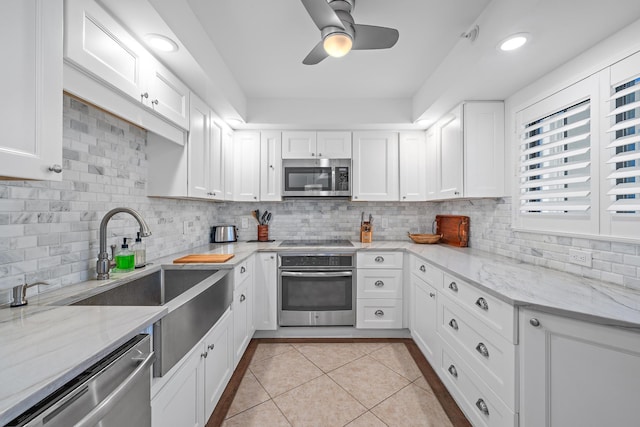 kitchen with backsplash, light stone countertops, light tile patterned floors, appliances with stainless steel finishes, and white cabinetry