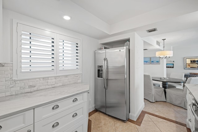 kitchen featuring backsplash, white cabinets, hanging light fixtures, light stone counters, and stainless steel fridge with ice dispenser