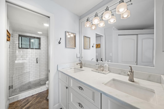 bathroom with parquet flooring, vanity, toilet, and an enclosed shower