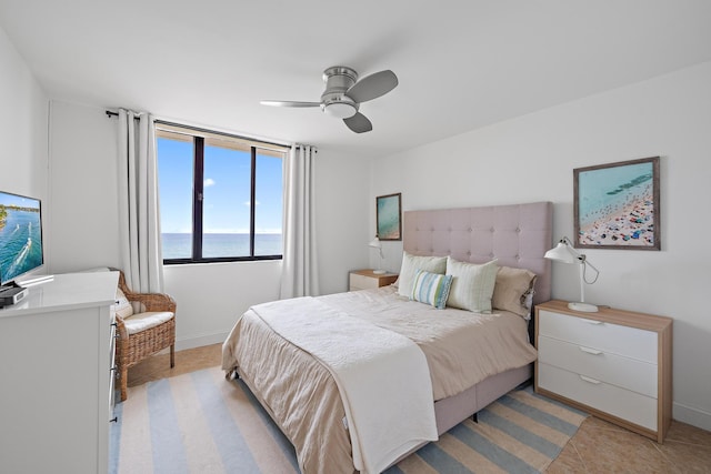 bedroom featuring ceiling fan, a water view, and light tile patterned floors