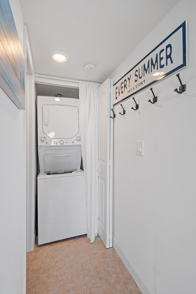 corridor with stacked washer and dryer and light tile patterned floors