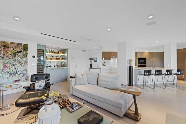 living room with light hardwood / wood-style floors and indoor wet bar