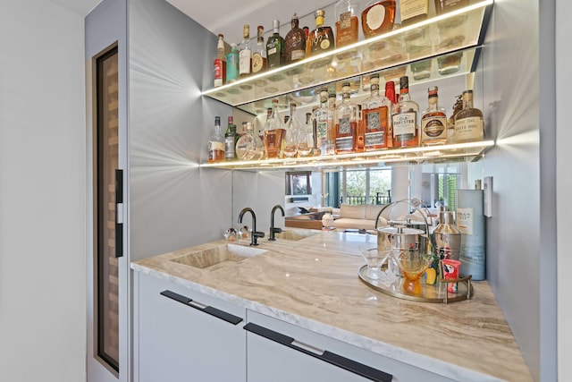 bar featuring light stone counters and sink