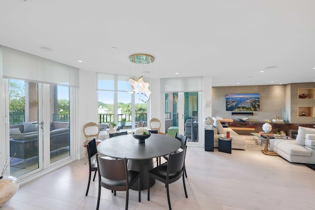 dining space with an inviting chandelier, light wood-type flooring, and french doors