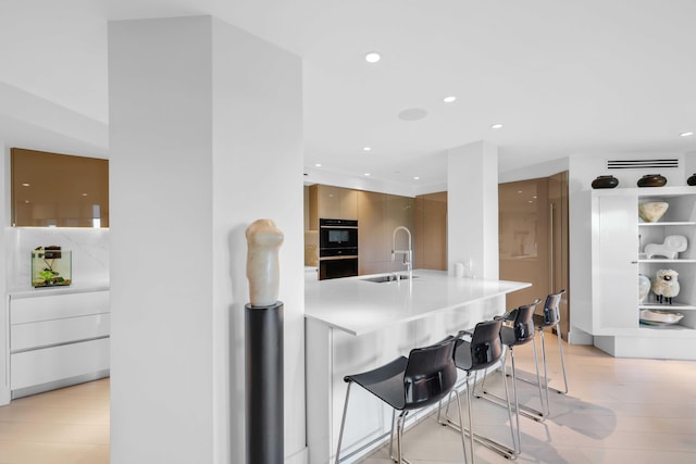 kitchen with a kitchen bar, sink, and black double oven