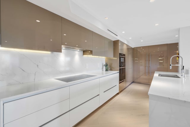 kitchen with light stone countertops, sink, decorative backsplash, white cabinets, and black appliances