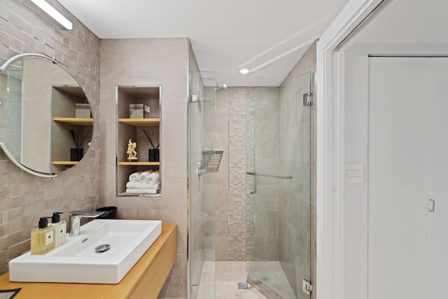 bathroom with a shower with door, sink, and tile walls