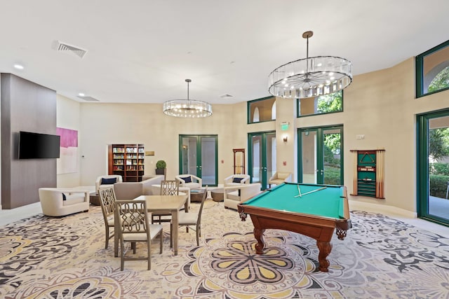 game room with a towering ceiling, french doors, billiards, and an inviting chandelier