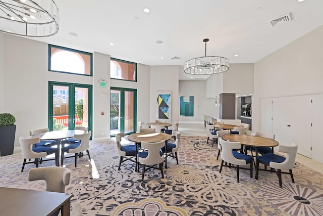 dining area with a chandelier, a high ceiling, and french doors