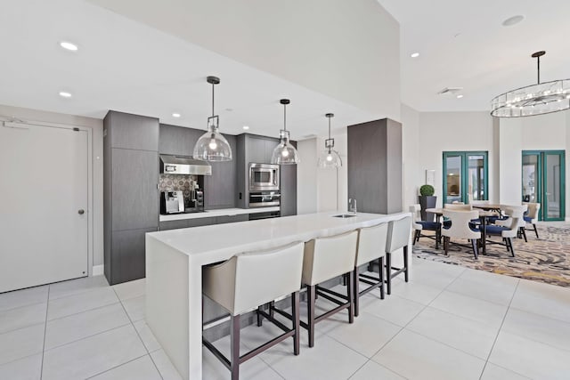 kitchen featuring appliances with stainless steel finishes, light tile patterned floors, hanging light fixtures, and a kitchen breakfast bar