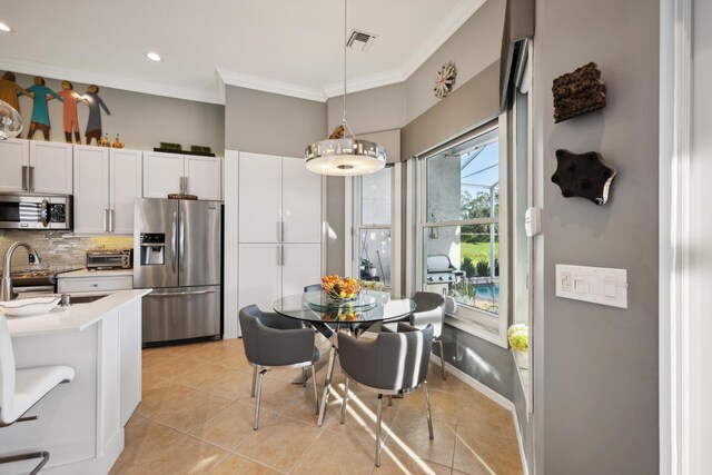 kitchen with light tile patterned floors, stainless steel appliances, decorative backsplash, decorative light fixtures, and white cabinets