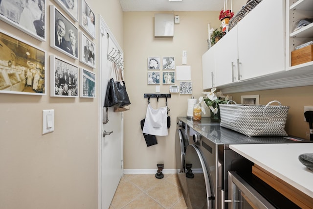 washroom featuring light tile patterned floors, washer and dryer, and cabinets