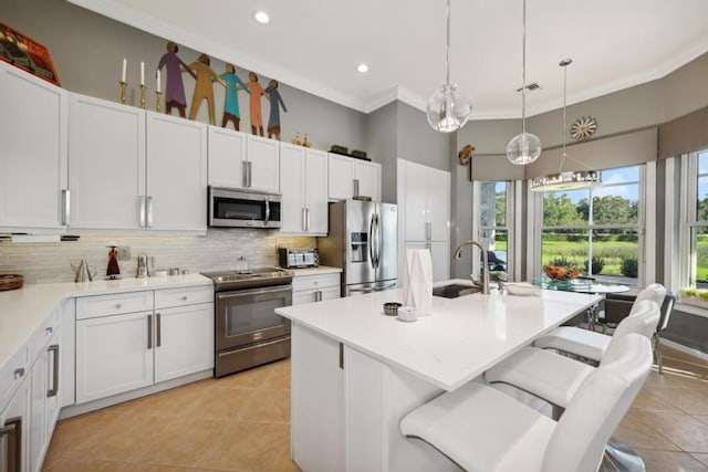 kitchen featuring decorative light fixtures, a kitchen bar, appliances with stainless steel finishes, and white cabinetry