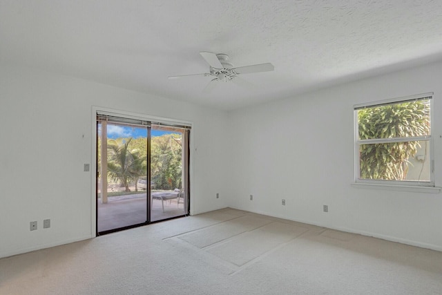 carpeted empty room featuring a textured ceiling, ceiling fan, and a healthy amount of sunlight