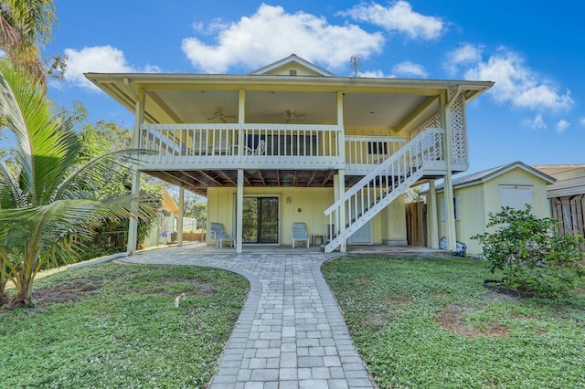 back of house with a lawn, a patio area, ceiling fan, and a storage shed